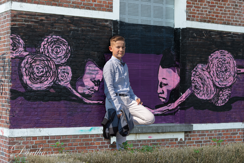Communiefoto jonge kerel voor een paarse graffititekening in centrum Doel